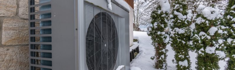 Air heat pump beside house in snow